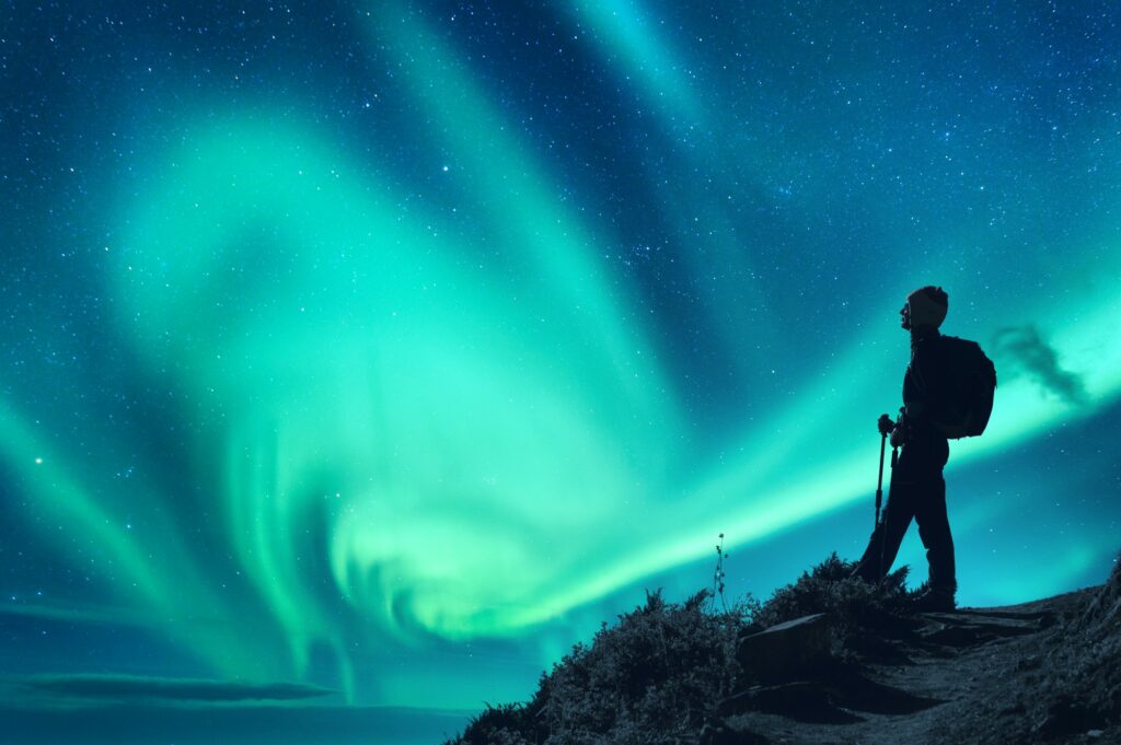 Aurora borealis and silhouette of a woman with backpack at night