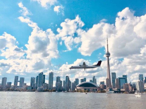 Regional jet coming in for a landing with Toronto cityscape in the background.